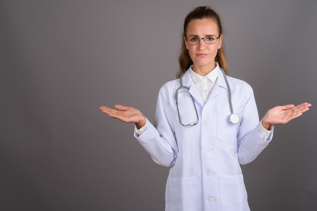 Young beautiful woman doctor against gray background