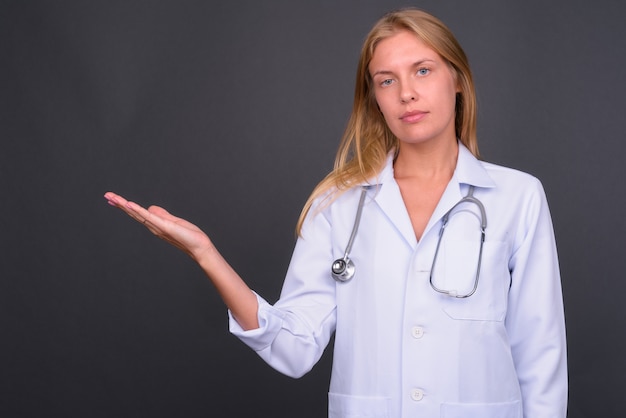  young beautiful woman doctor with blond hair against gray wall