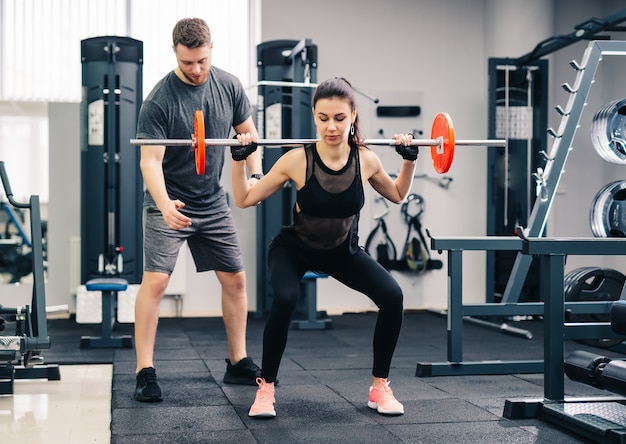 Young beautiful woman doing exercises with personal trainer. 