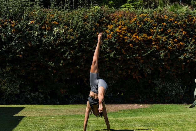 Young and beautiful woman doing gymnastics in the garden of her house