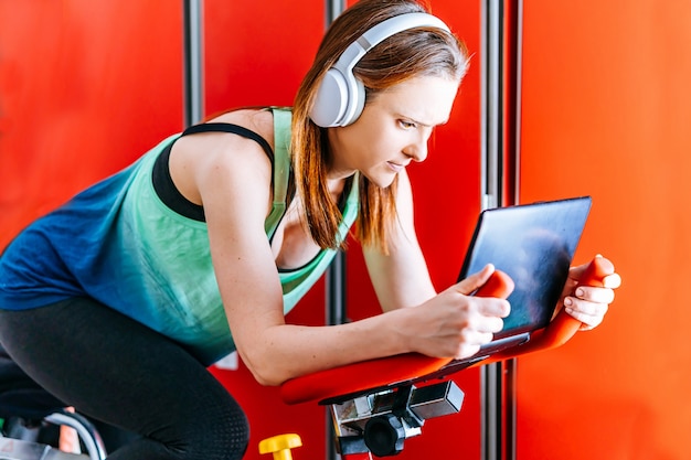 Photo young beautiful woman doing sports with music headphones looking at the screen of a laptop