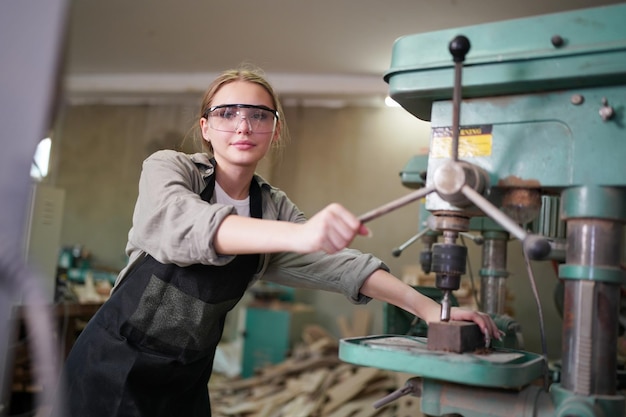 Young beautiful woman doing work in the carpenter DIY workshop room. Small Business owner, young woman who working at furniture factory.