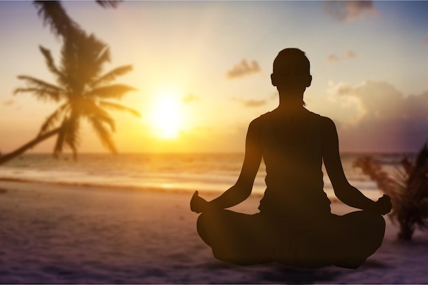 Young beautiful woman doing yoga at sunset