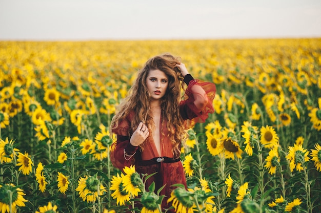 Young beautiful woman in a dress among blooming sunflowers. Agro-culture. 