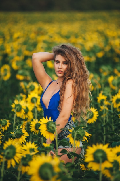 Young beautiful woman in a dress among blooming sunflowers. Agro-culture. 