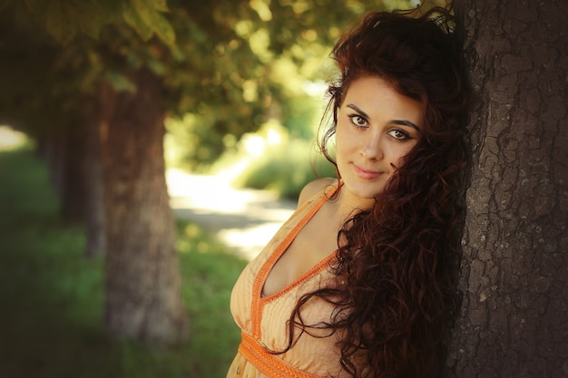 Young beautiful woman in a dress near the tree