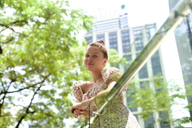 春または夏の晴れた日に街を歩くドレスを着た若い美しい女性