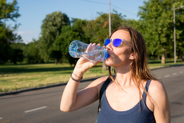 Young beautiful woman drinking bottle of water