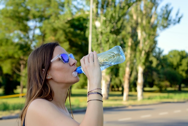 水の瓶を飲む若い美しい女性