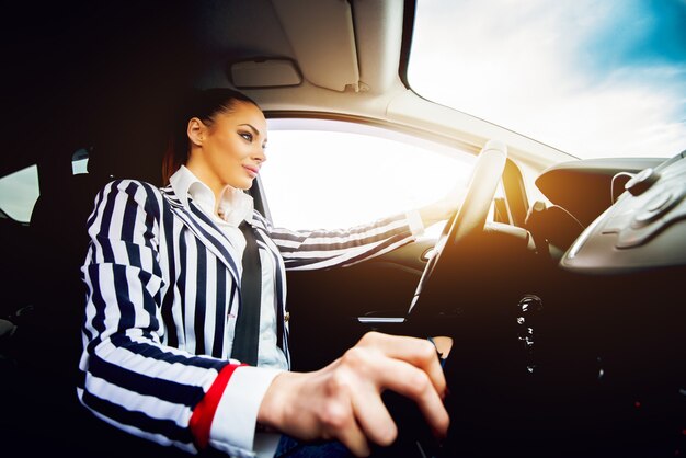 車のシフトギアを運転する若い美しい女性。