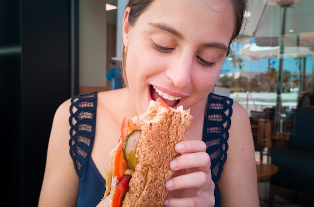 Giovane bella donna che mangia un panino