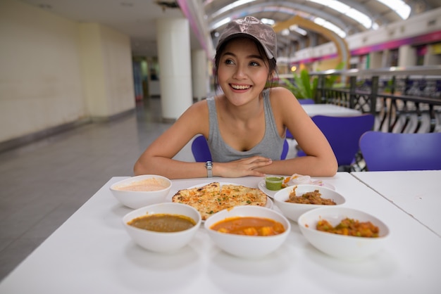 Young beautiful woman enjoying Indian food at restaurant