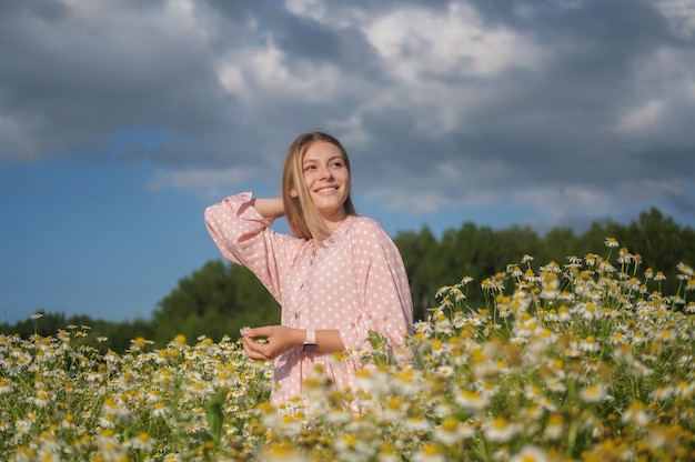 Young beautiful woman on the field with white daisies