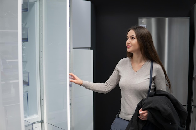 Young beautiful woman finding herself refrigerator or fridge in a store supermarket shop.