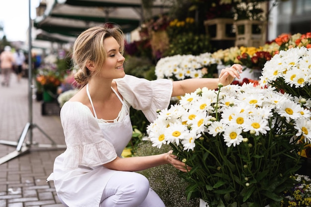 彼女の小さな花屋で働く若くて美しい女性の花屋