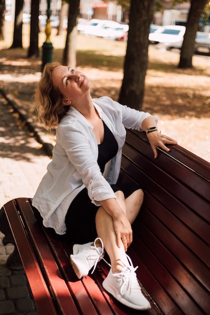 Young beautiful woman freelancer sitting on a park bench