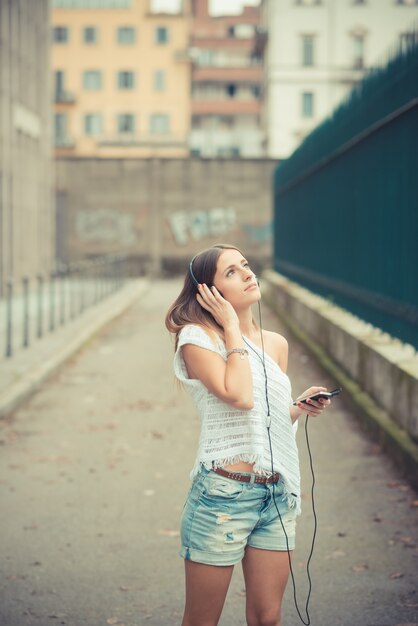 若い美しい女の子の秋の音楽を聞く