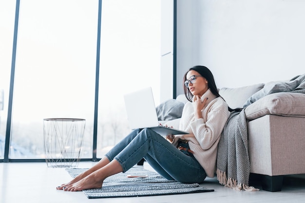 Young beautiful woman in glasses sitting at home alone with laptop.