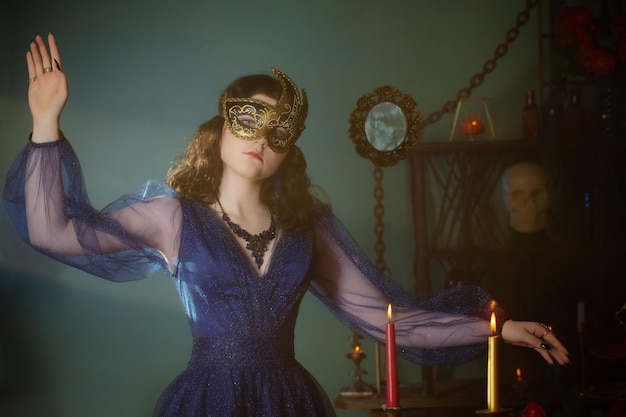 Photo young beautiful woman in golden mask and blue vintage dress in dark room