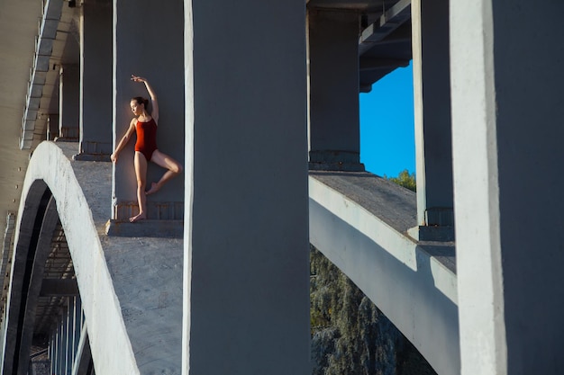 Young beautiful woman gymnast posing on bridge girder