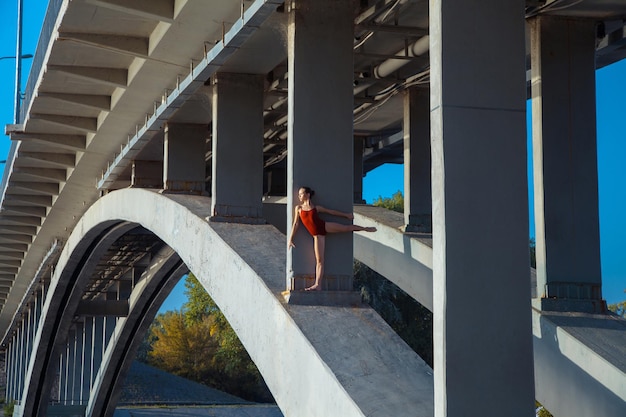 Foto giovane bella ginnasta della donna che posa sulla trave del ponte