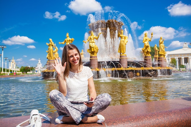 Young beautiful woman has a rest sitting near the fountain of friendship of the people daily view at vdnh exhibition in moscow russia