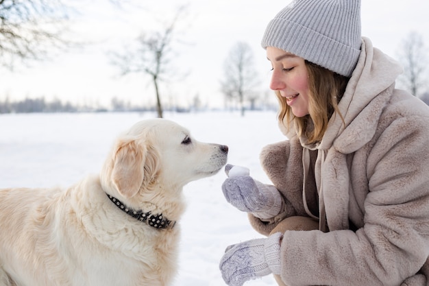 Young beautiful woman and her golden retriever dog having fun in winter