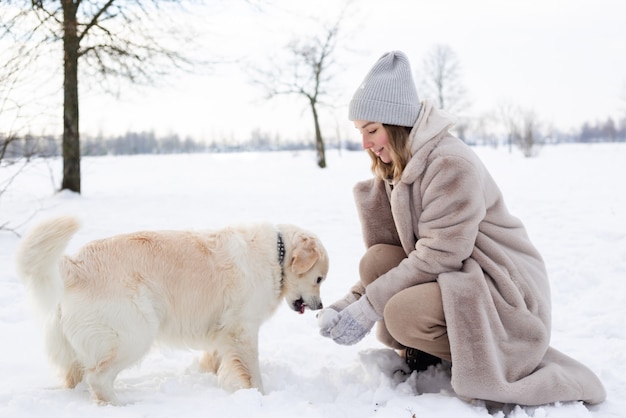 Young beautiful woman and her golden retriever dog having fun in winter