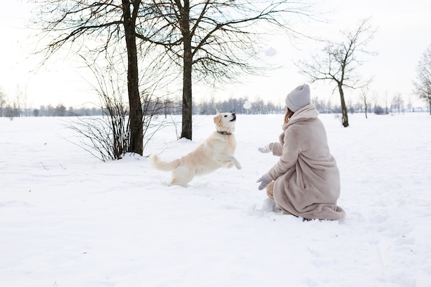 Young beautiful woman and her golden retriever dog having fun in winter