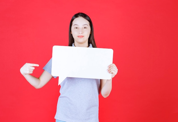 Young beautiful woman holding board and point finger on it