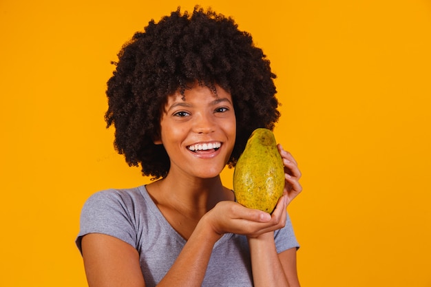 Photo young beautiful woman holding papaya on yellow