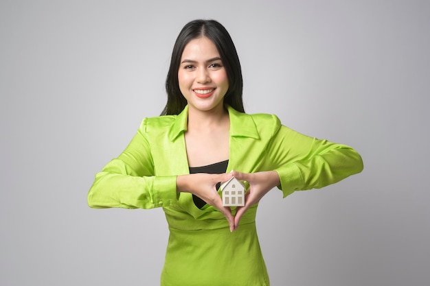 Young beautiful woman holding small model house over white background studiox9