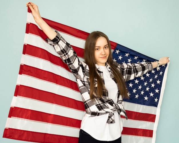 Young beautiful woman holding USA flag on a blue