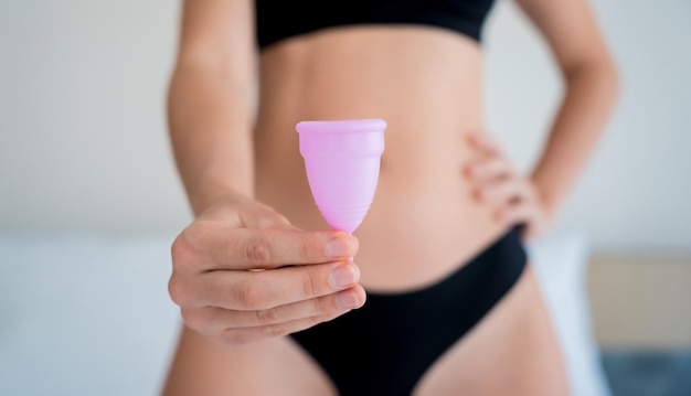 Young beautiful woman at home holding a menstrual cup in her hands