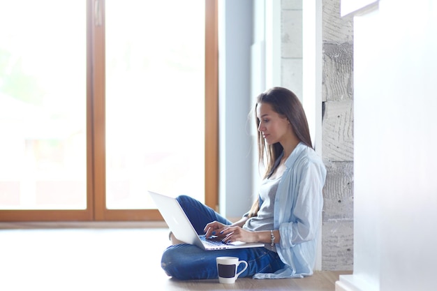 Young beautiful woman at home sitting on the floor with laptop Young beautiful woman