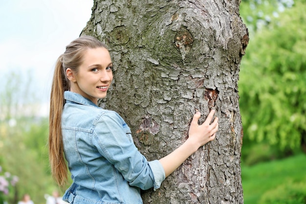 Young beautiful woman hugging tree trunk