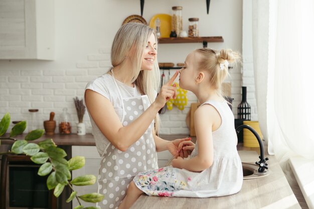 Young beautiful woman hugs and kisses her cute little daughter. Toning.