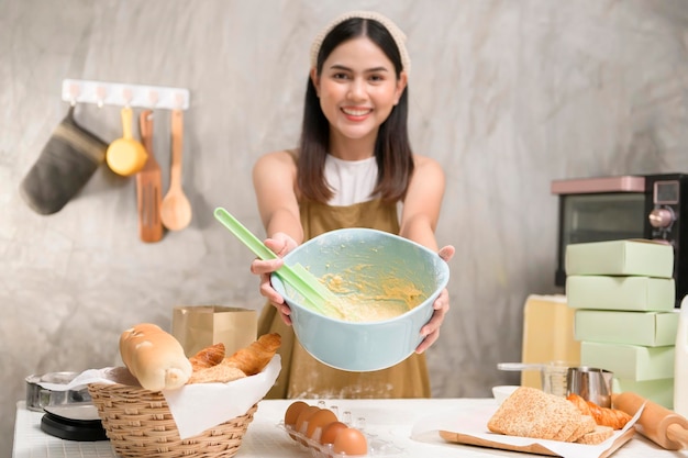 La giovane bella donna sta cuocendo nella sua attività di panetteria e caffetteria in cucina