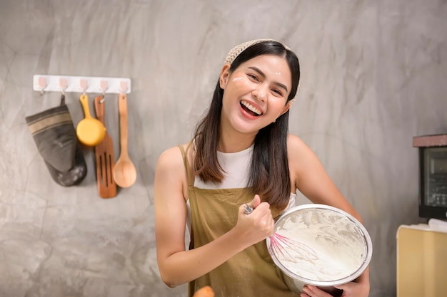 La giovane bella donna sta cuocendo nella sua attività di panetteria e caffetteria in cucina