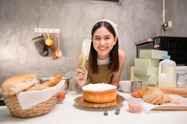 La giovane bella donna sta cuocendo nella sua attività di panetteria e caffetteria in cucina