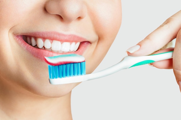 Фото Молодая красивая женщина занимается чисткой зубов красивая улыбка здоровые белые зубы девушка держит зубную щетку концепция гигиены полости рта рекламное изображение стоматологической стоматологической клиники