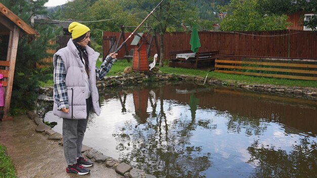 Young beautiful woman is fishing in a small pond