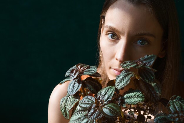 Young beautiful woman is holding home plants up to her face she takes care of houseplants woman plan...