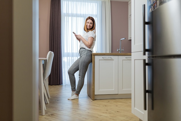 A young beautiful woman is resting from housework when a robot vacuum cleaner cleans the apartment