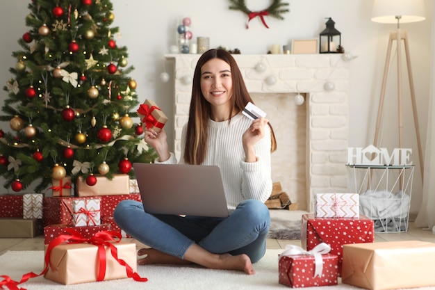 Young beautiful woman is shopping for christmas in festive interior at home