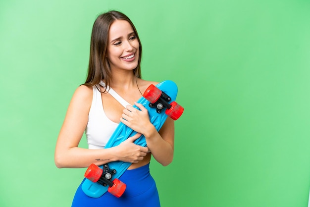 Young beautiful woman over isolated chroma key background with a skate with happy expression