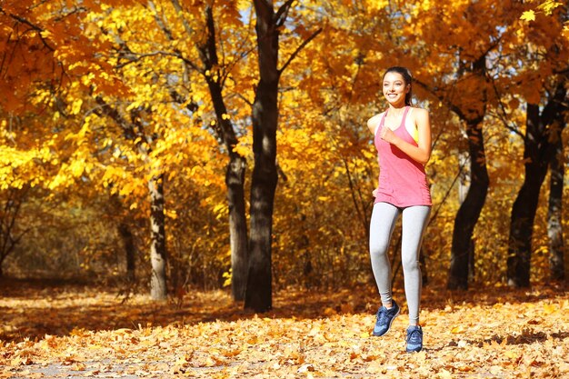 Young beautiful woman jogging in autumn park