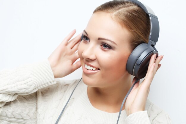 Young beautiful woman listening the music from headphones over white space