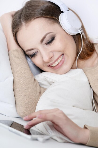 Young beautiful woman listening to music on sofa at home