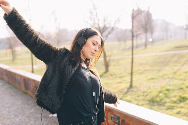 Giovane bella donna che ascolta la musica con le cuffie